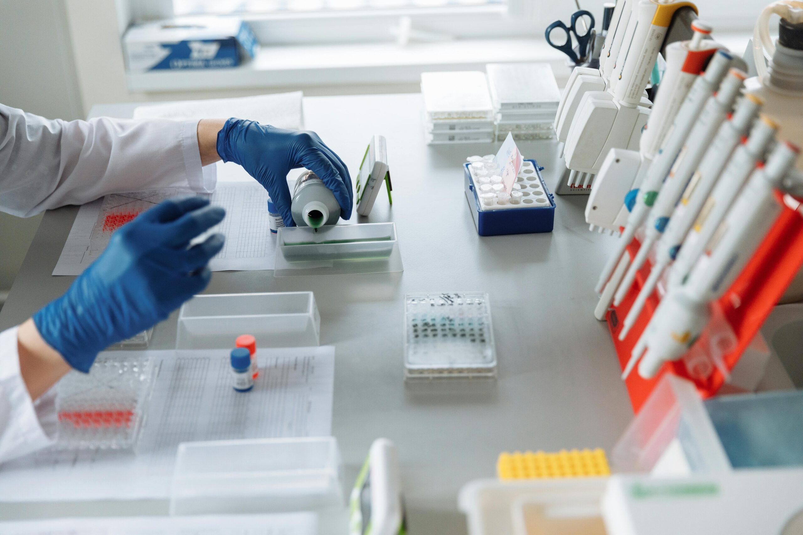 Scientist in blue gloves handling lab equipment and samples.